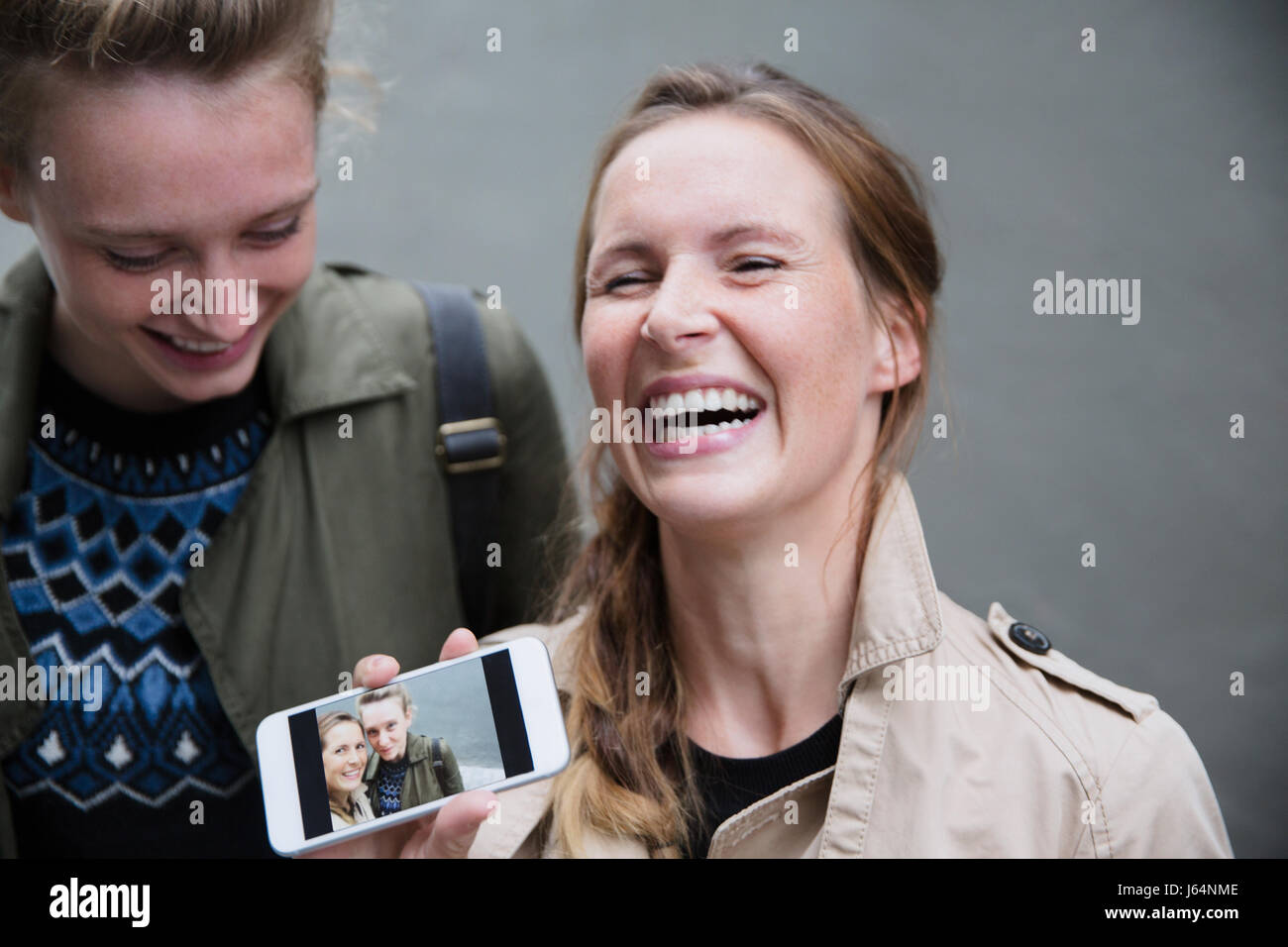 Laughing young women showing selfie photograph on smart phone Stock Photo