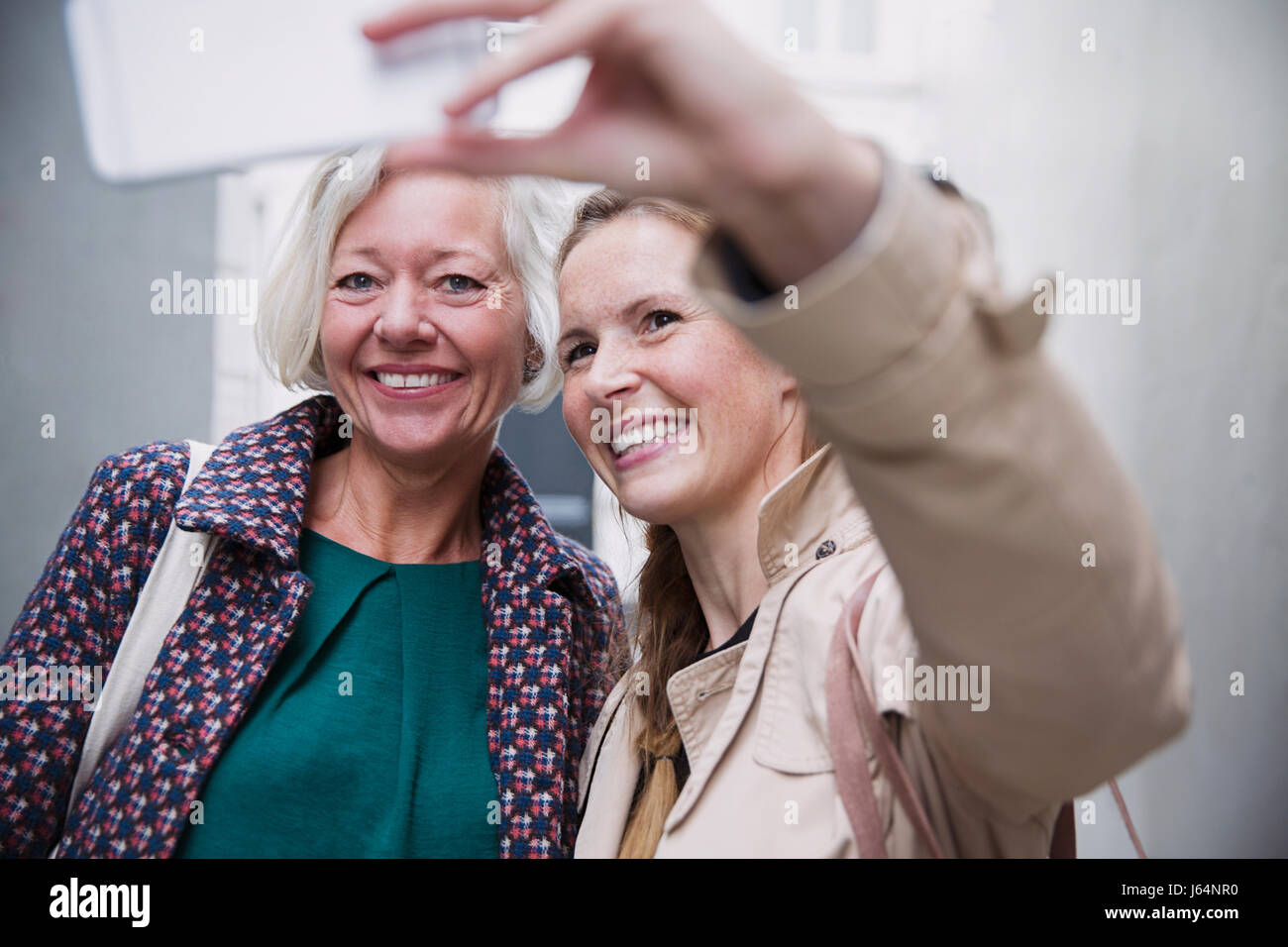 Smiling mother and daughter taking selfie with camera phone Stock Photo