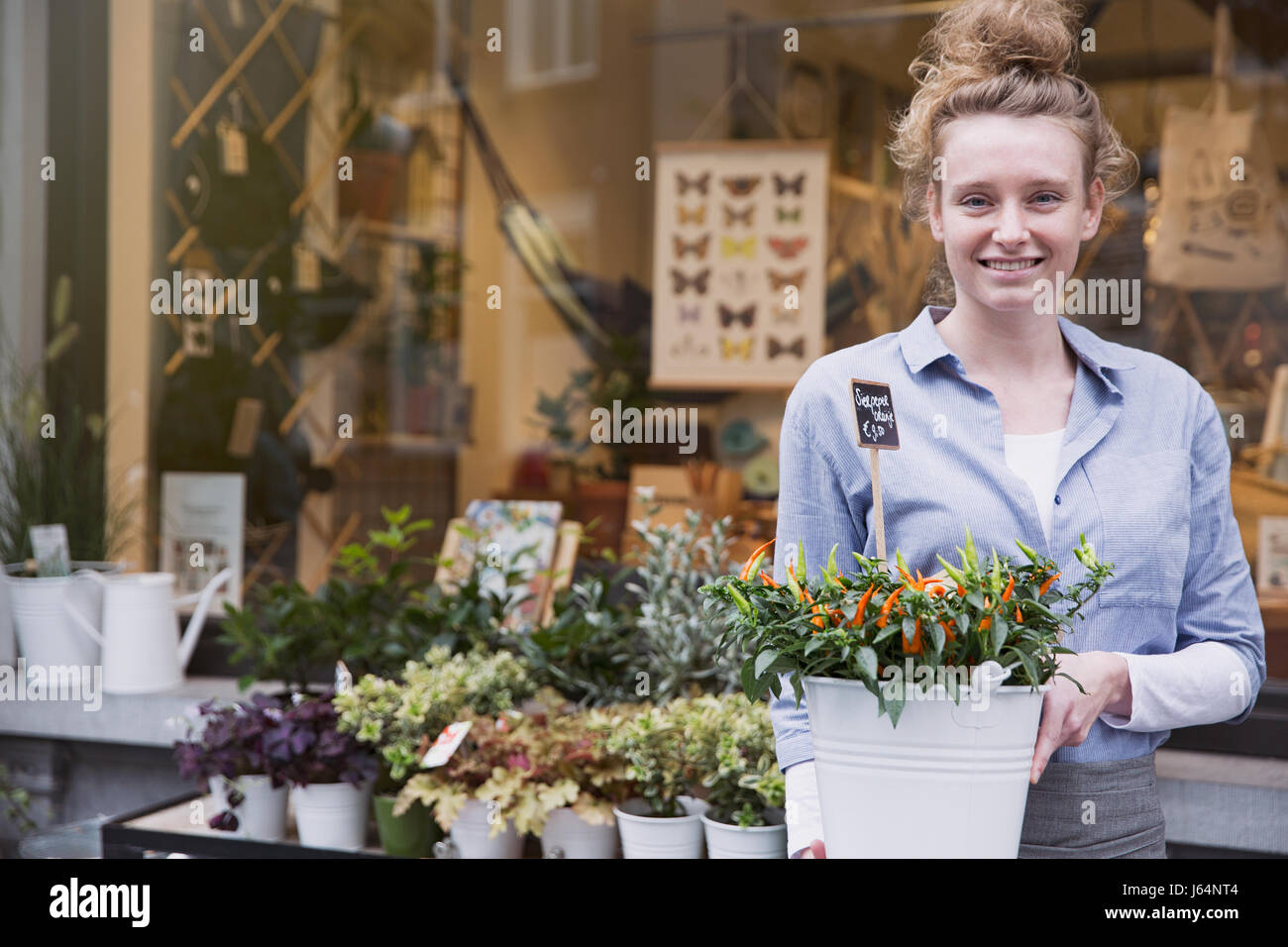 Portrait smiling female florist with potted plant at storefront Stock Photo