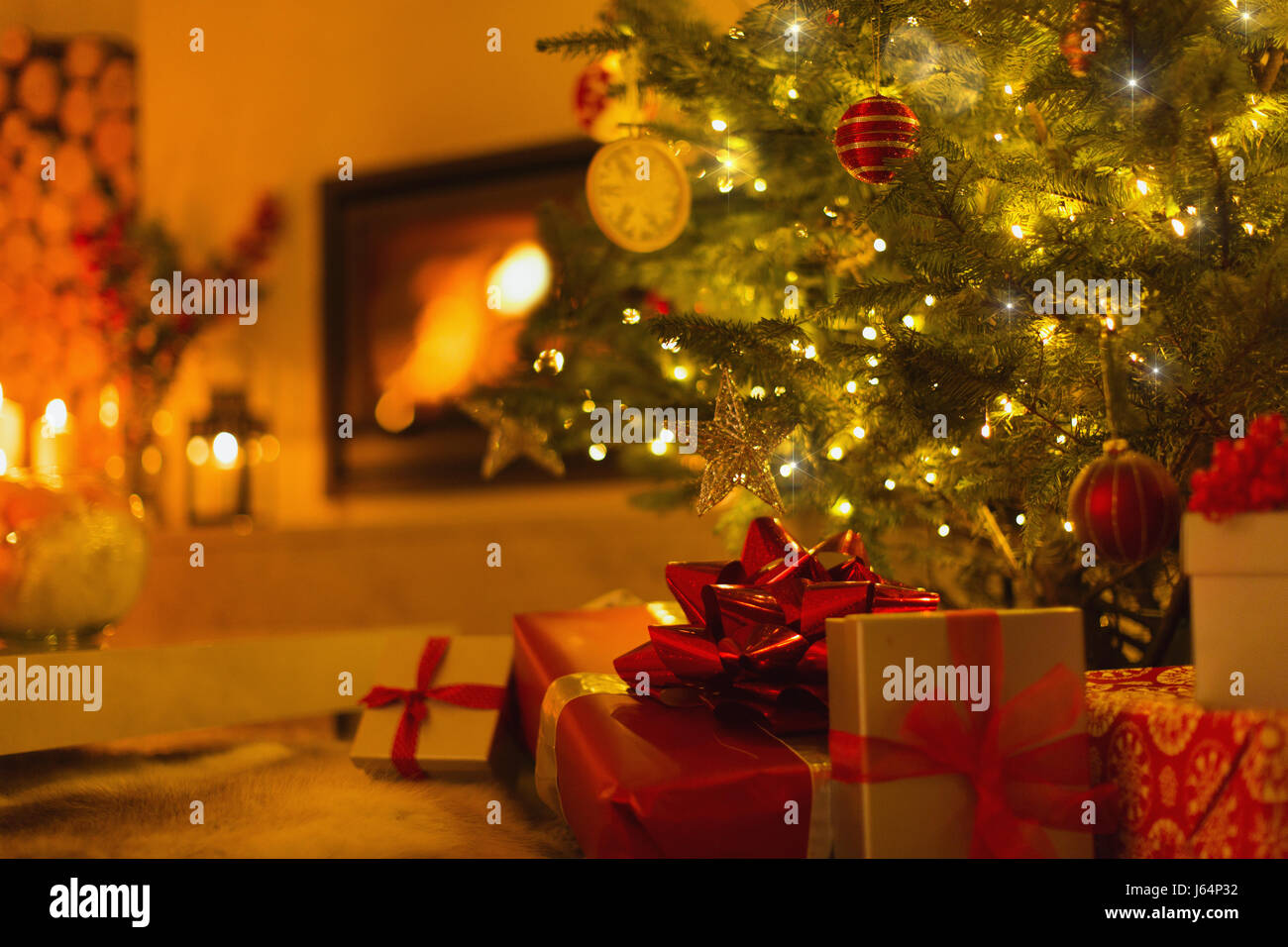 Gifts under Christmas tree in ambient living room with fireplace Stock Photo