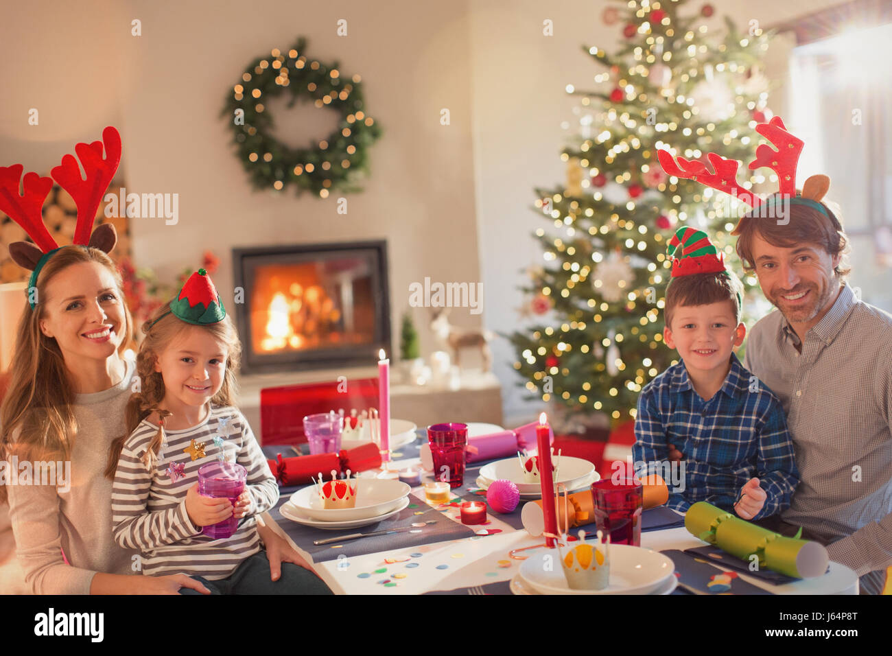 Portrait smiling young family wearing costume reindeer antlers at Christmas dinner table Stock Photo