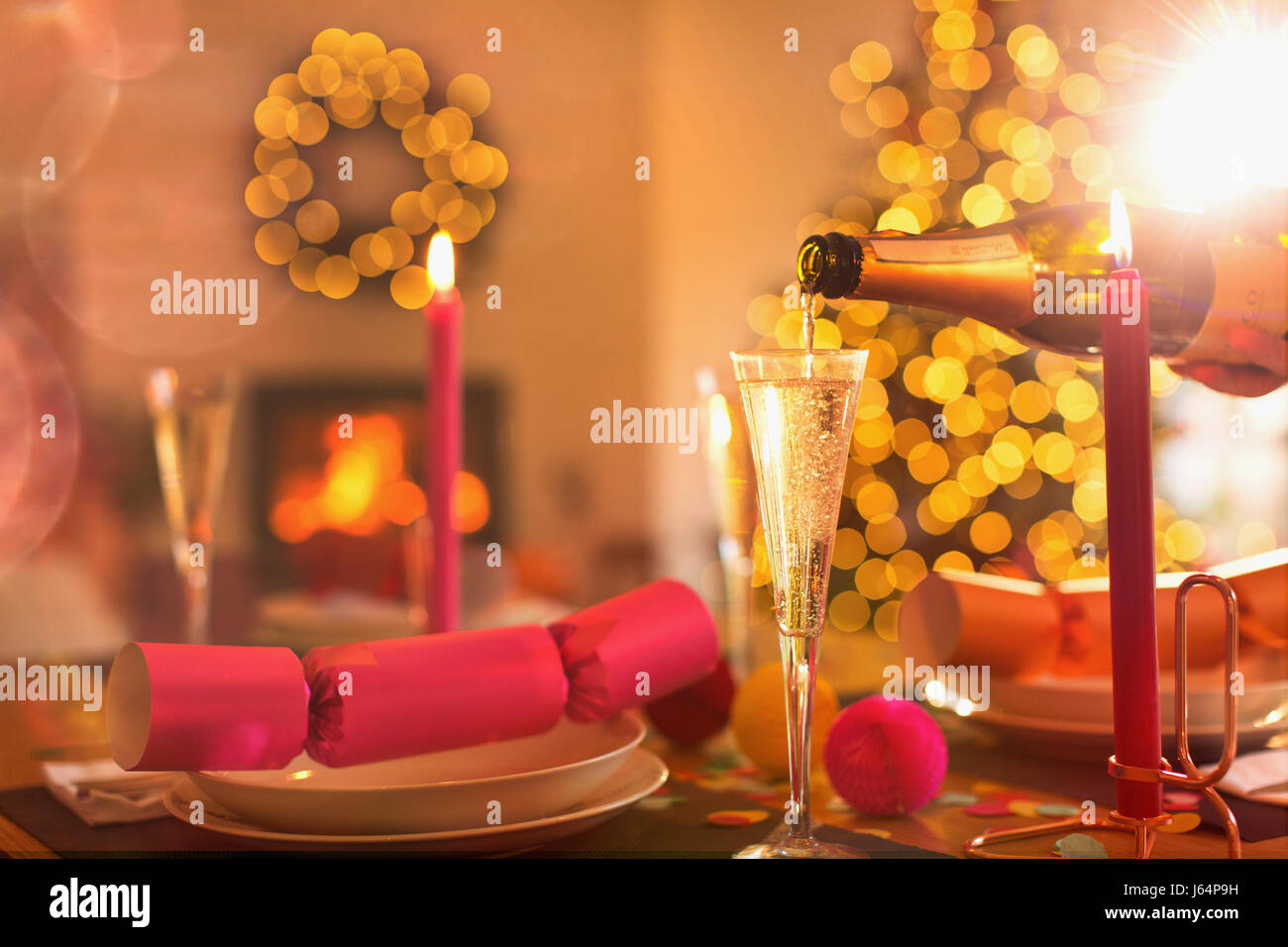 Pouring champagne into champagne flute on Christmas dinner table with Christmas cracker Stock Photo