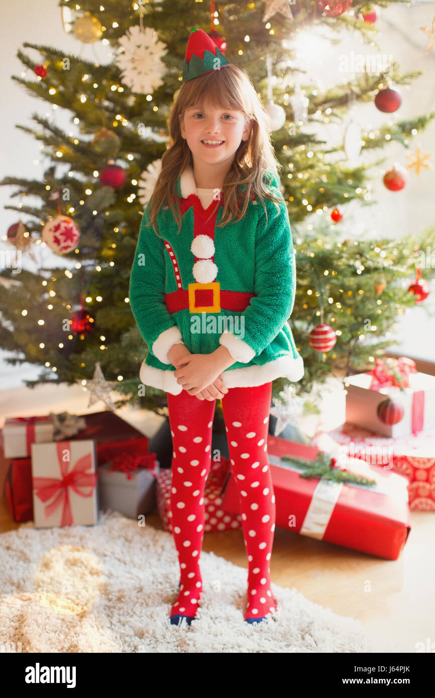 Portrait smiling girl wearing elf costume in front of Christmas tree Stock Photo