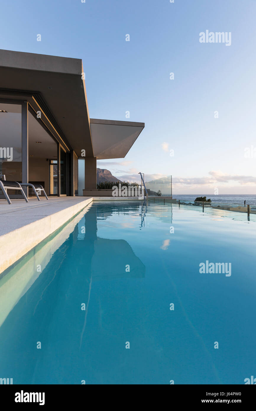 Tranquil blue lap swimming pool outside modern luxury home showcase exterior Stock Photo