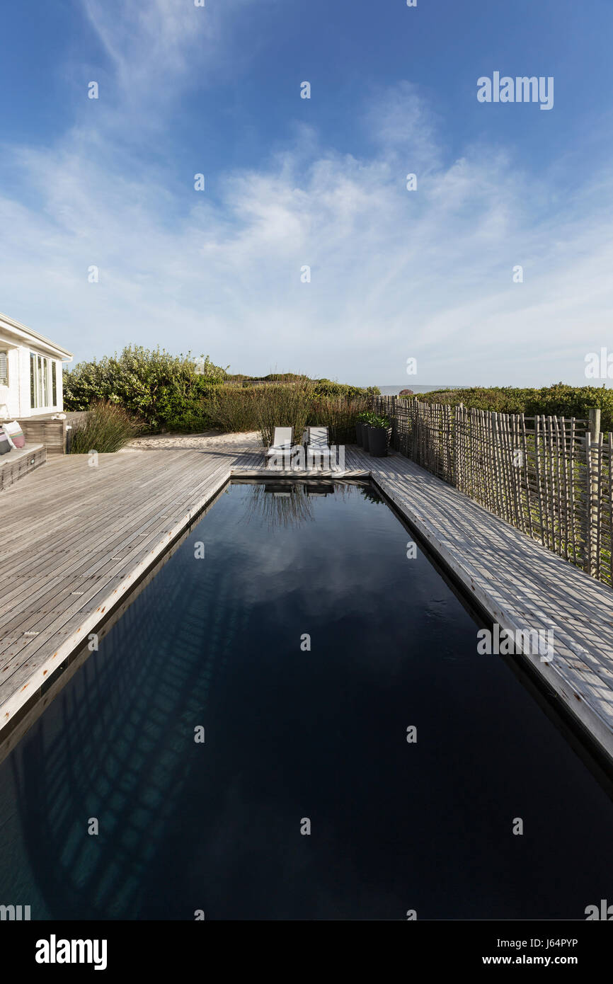Dark luxury swimming pool under sunny blue sky Stock Photo