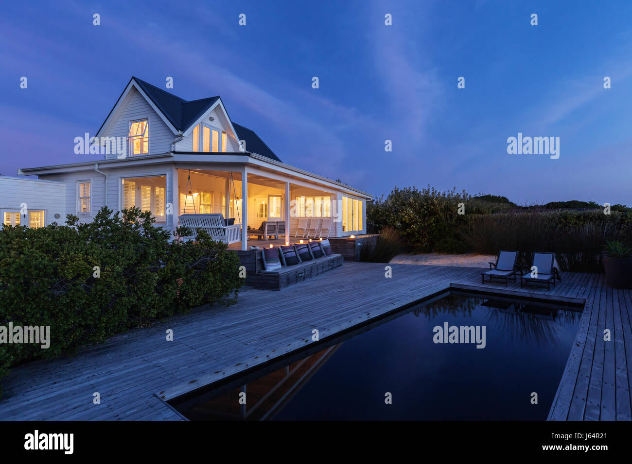 Illuminated white home showcase exterior and swimming pool at night Stock Photo