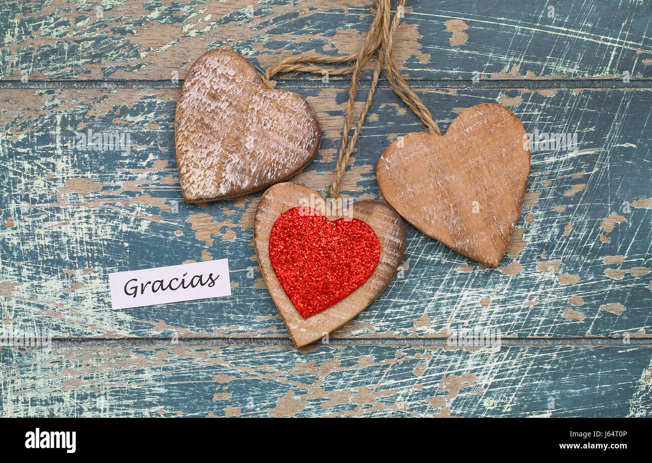 Gracias (thank you in Spanish) card with three wooden hearts on rustic wooden surface Stock Photo