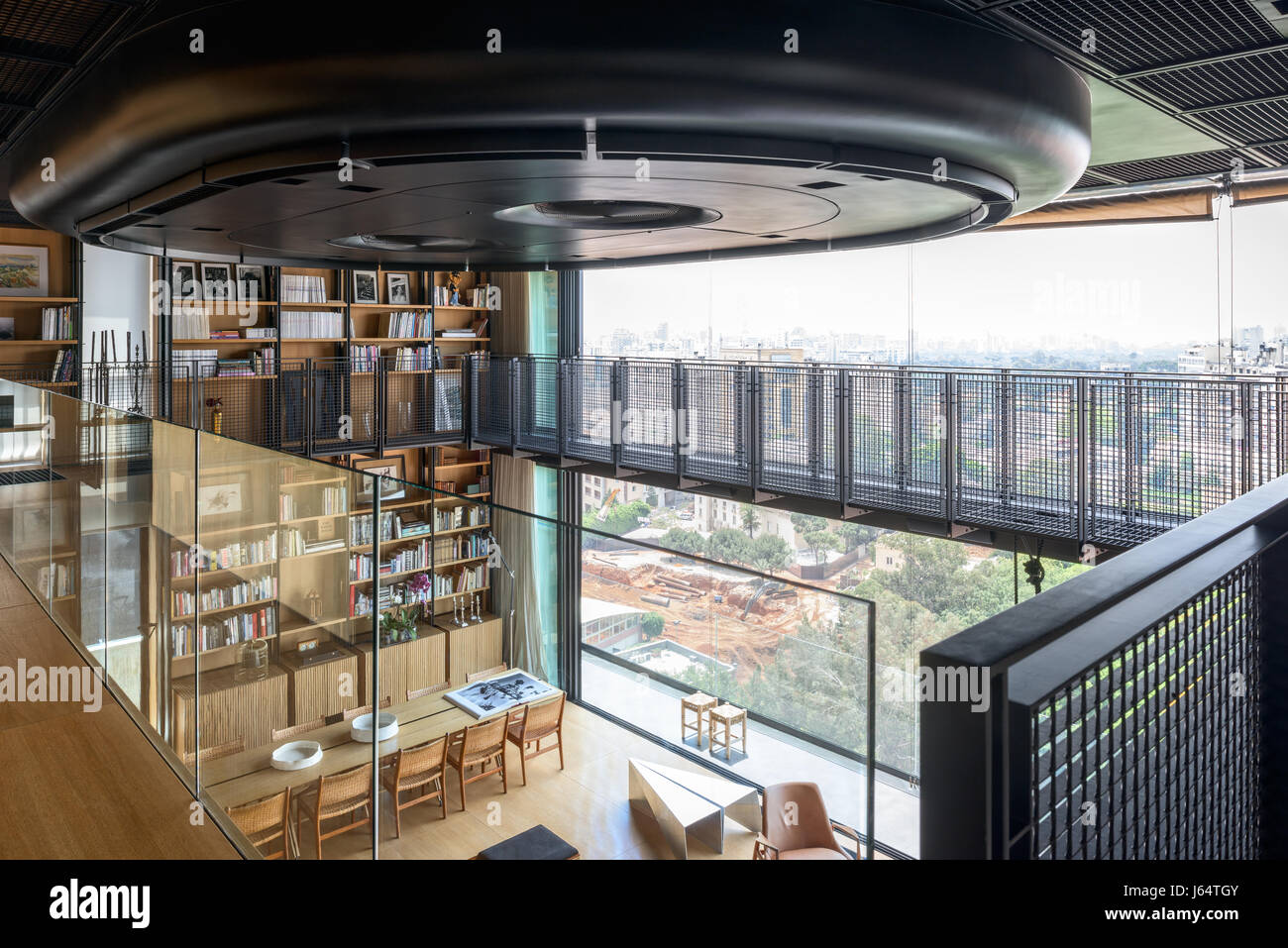 View from mezzanine level with glass balustrade of spacious double height living space with views of Beirut. The air conditioner is covered in a matt  Stock Photo