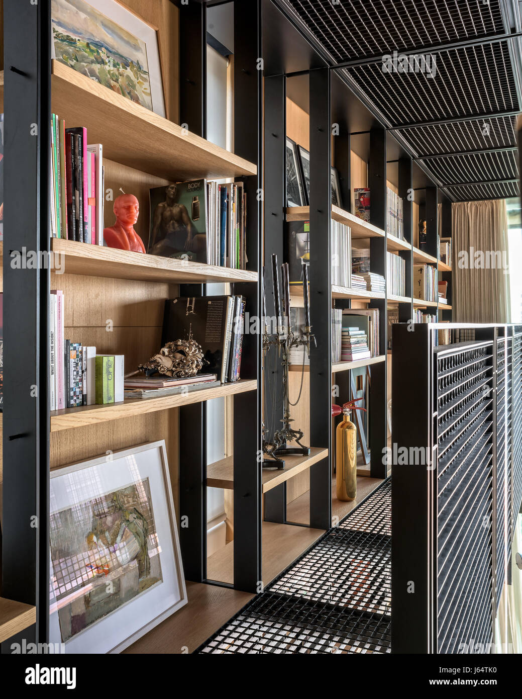 Black steel balcony lined with open shelving containing an assortment of art, books and collectibles Stock Photo