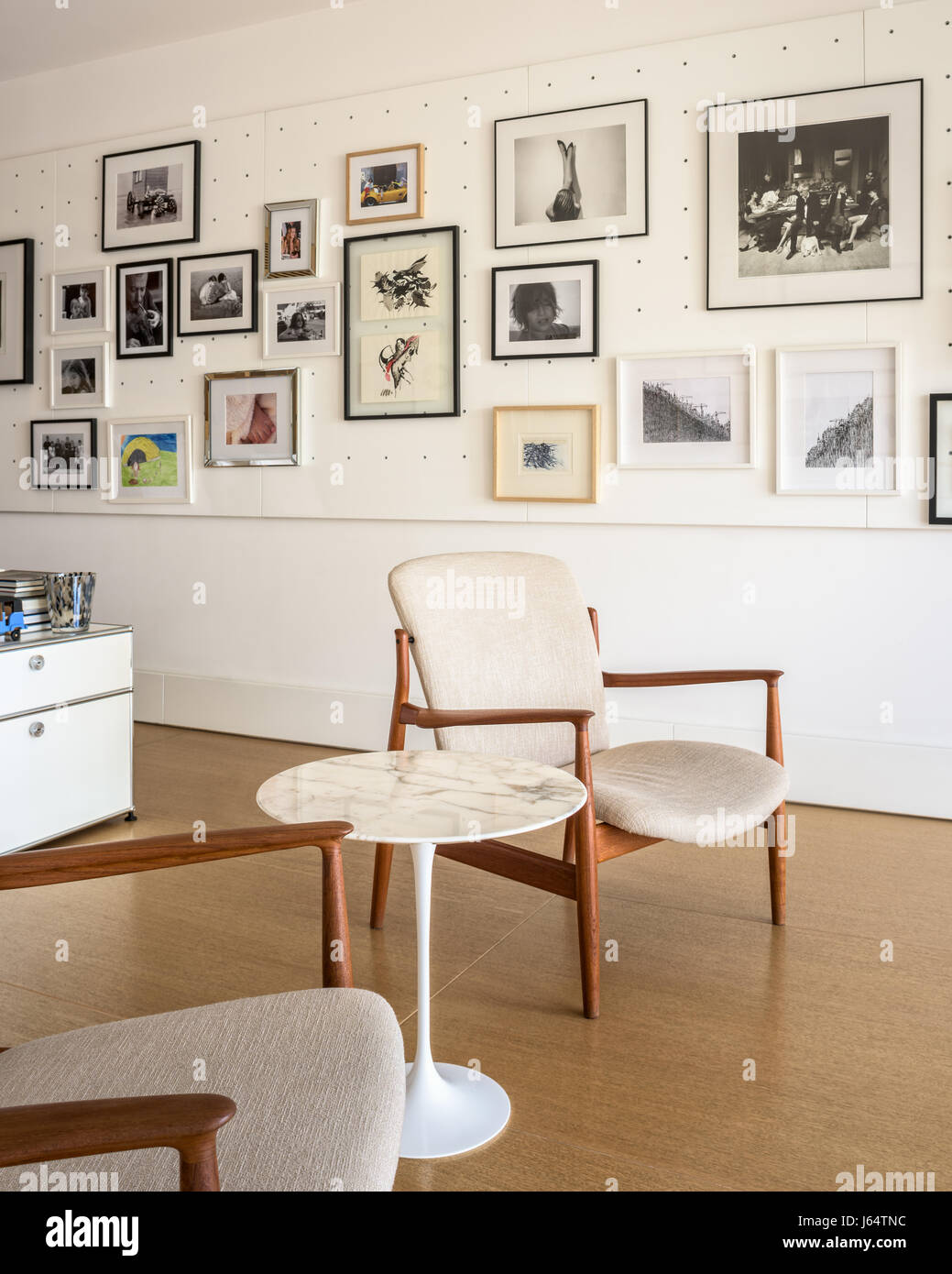 Pair of mid-century chairs and tulip side table by Eero Saarinen in bright master bedroom decorated with an assortment of art and photography. Stock Photo