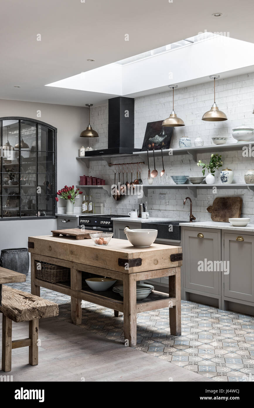 Open plan sophisticaed kitchen with vintage brass pendant lighting and rustic wooden butchers island Stock Photo