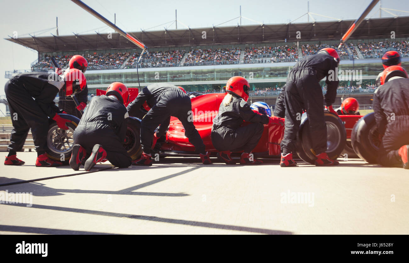 Pit crew replacing tires on formula one race car in pit lane Stock Photo