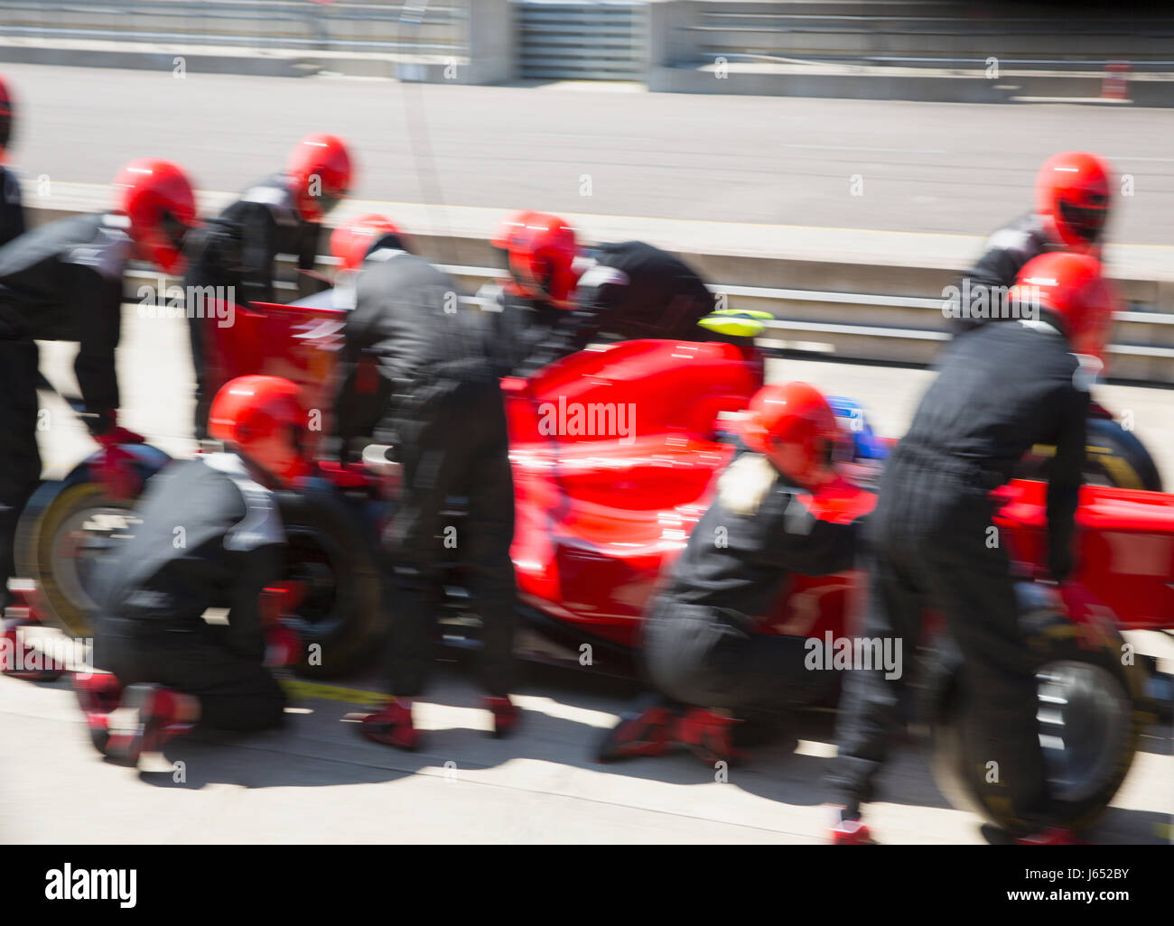 Pit crew replacing tires on formula one race car in pit lane Stock