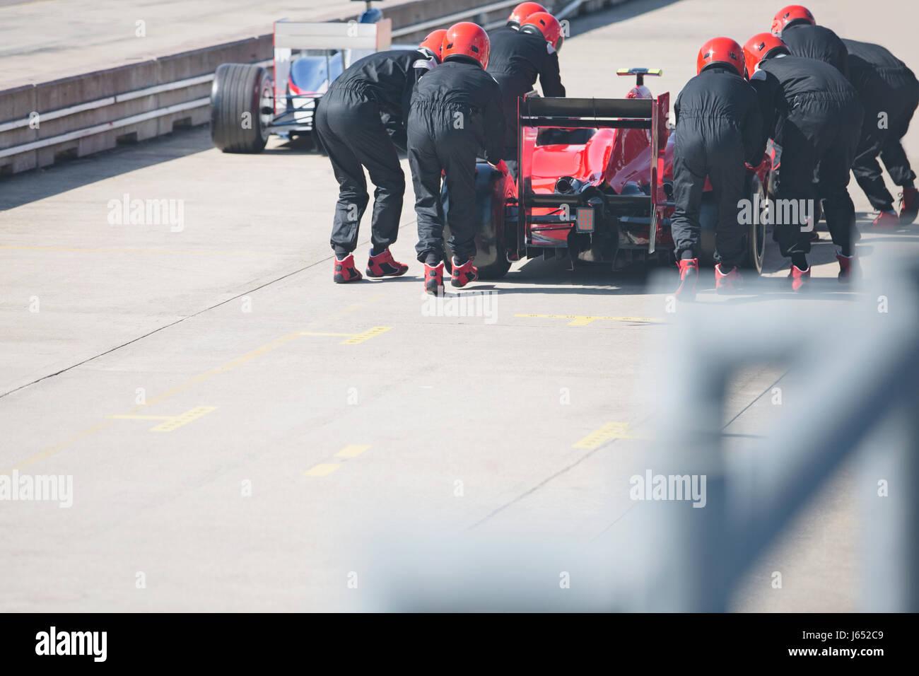 Pit crew pushing formula one race car out of pit lane Stock Photo