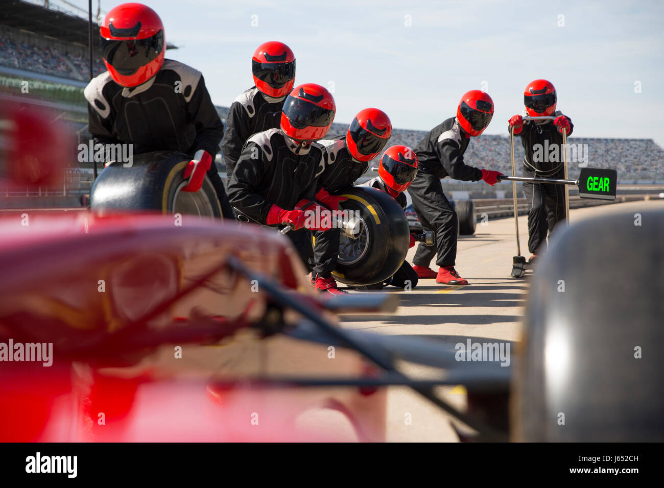 Pit crew with tires ready for nearing formula one race car in pit lane ...