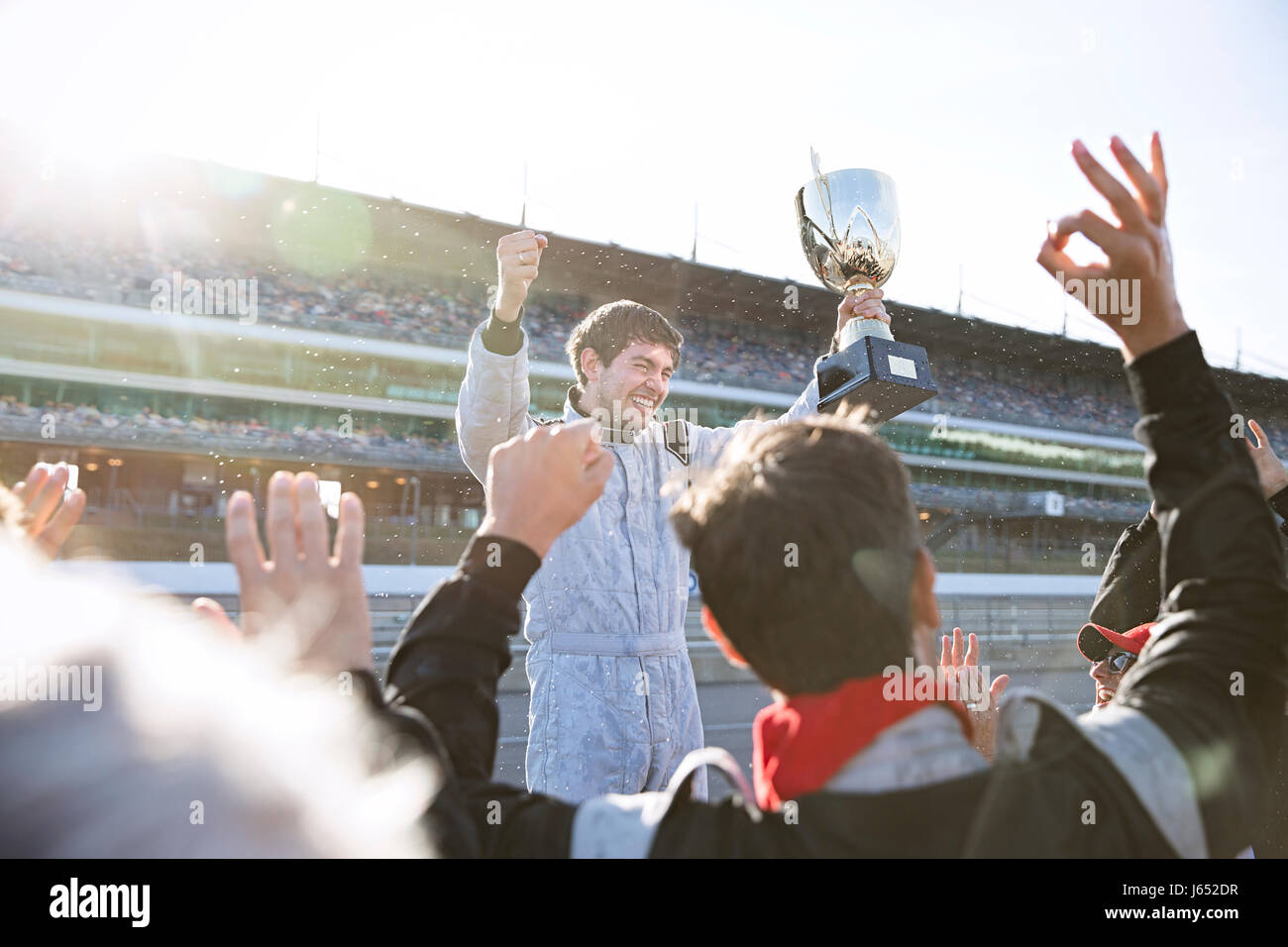 Formula one racing team cheering for driver with trophy, celebrating victory on sports track Stock Photo