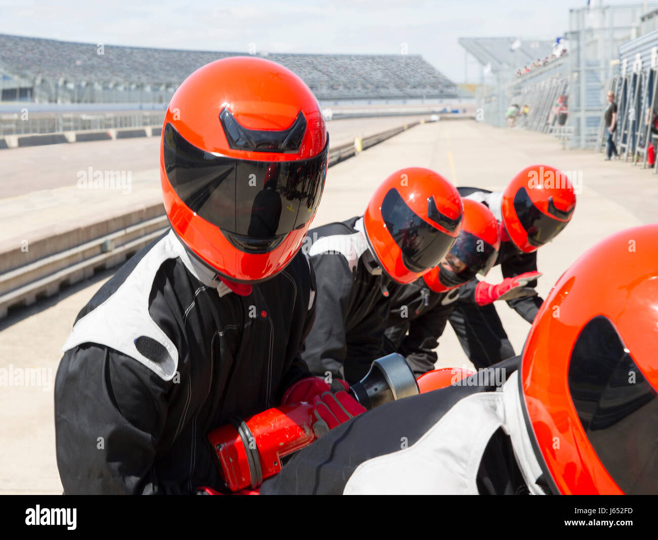 Pit crew wearing helmets in sunny pit lane Stock Photo