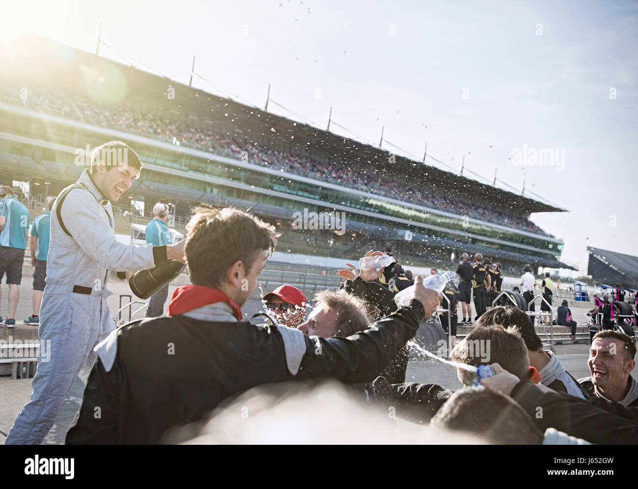 Formula one racing team and driver spraying champagne, celebrating victory on sports track Stock Photo