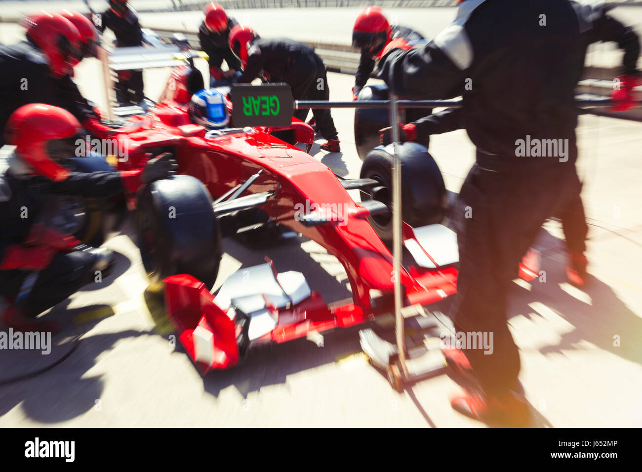 Pit crew replacing tires on formula one race car in pit lane Stock