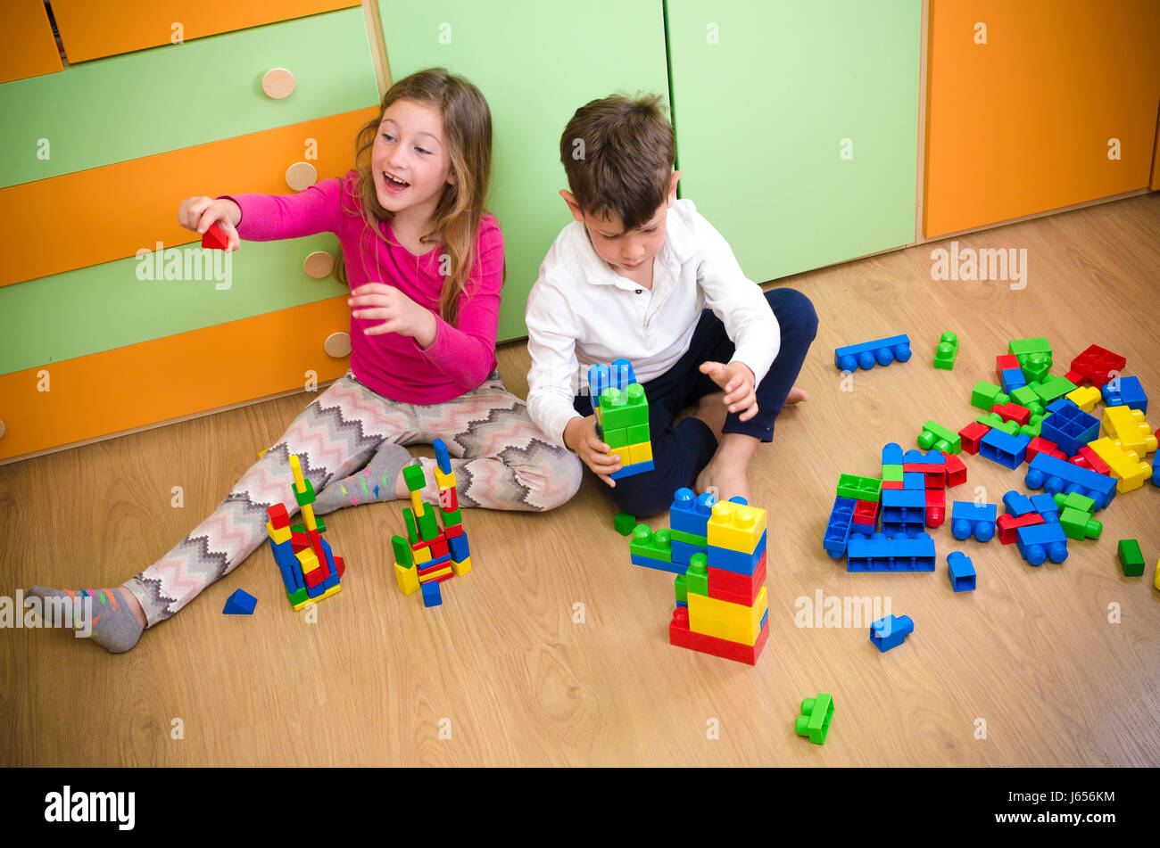 Children playing with construction toy blocks on floor of house Stock