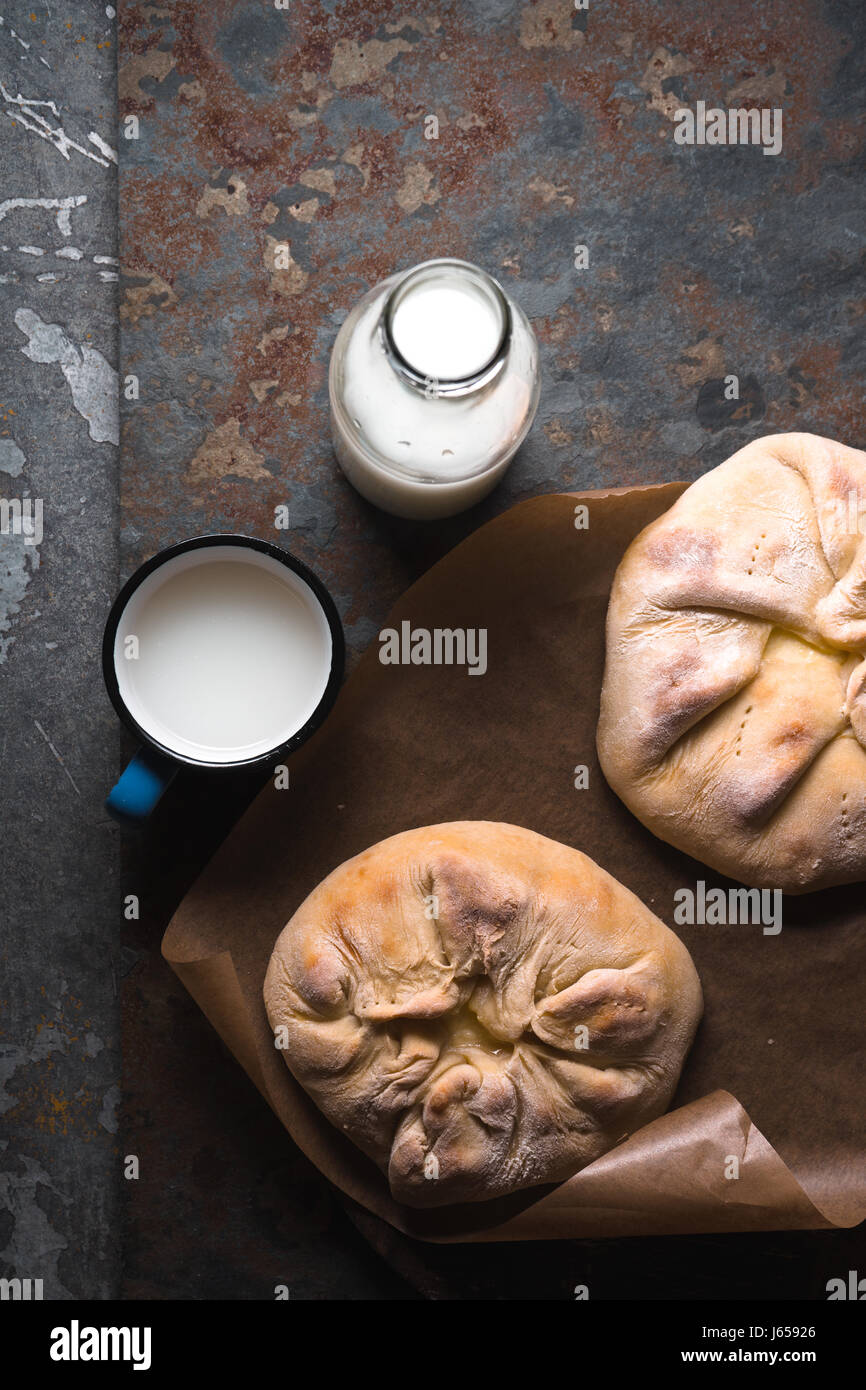 Ready-made khachapuri with cheese on parchment and milk in a bottle diagonal Stock Photo