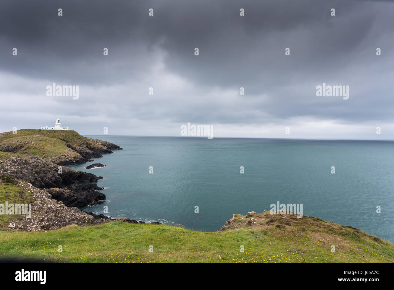 Lighthouse on a cliff with grey sky - Strumble Head, Wales, Great Britain, UK, Europe Stock Photo