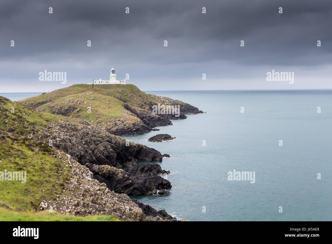 Lighthouse on a cliff with grey sky - Strumble Head, Wales, Great Britain, UK, Europe Stock Photo