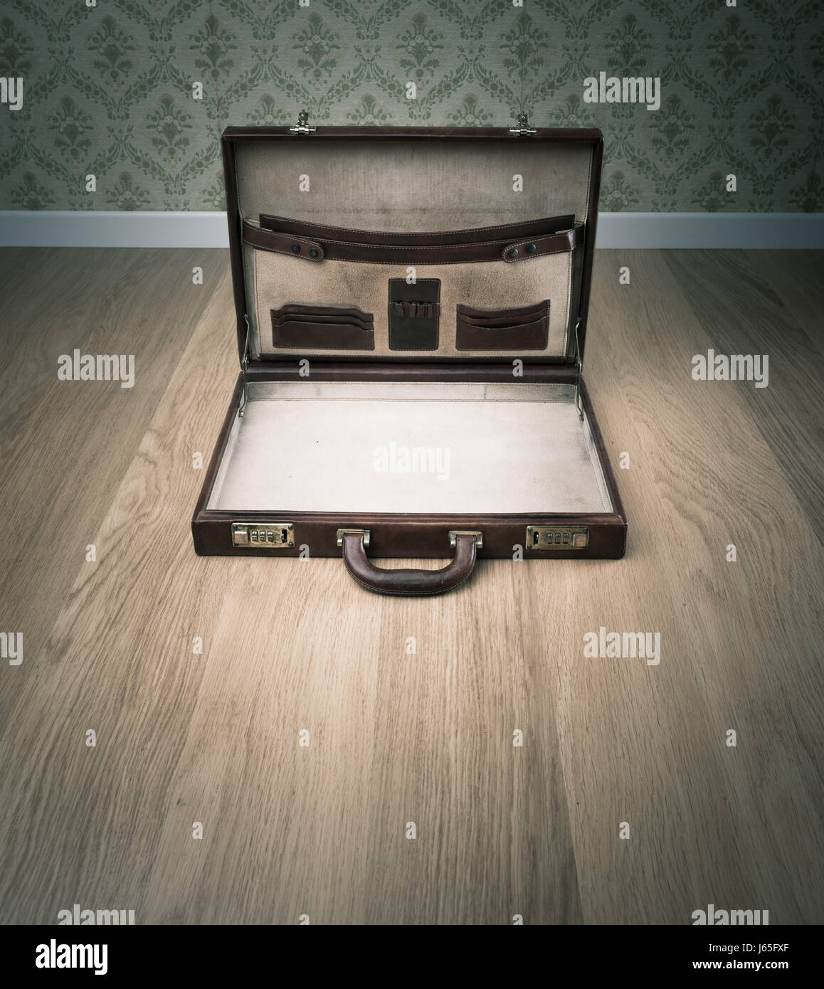 Open vintage leather briefcase on hardwood floor, retro wallpaper on