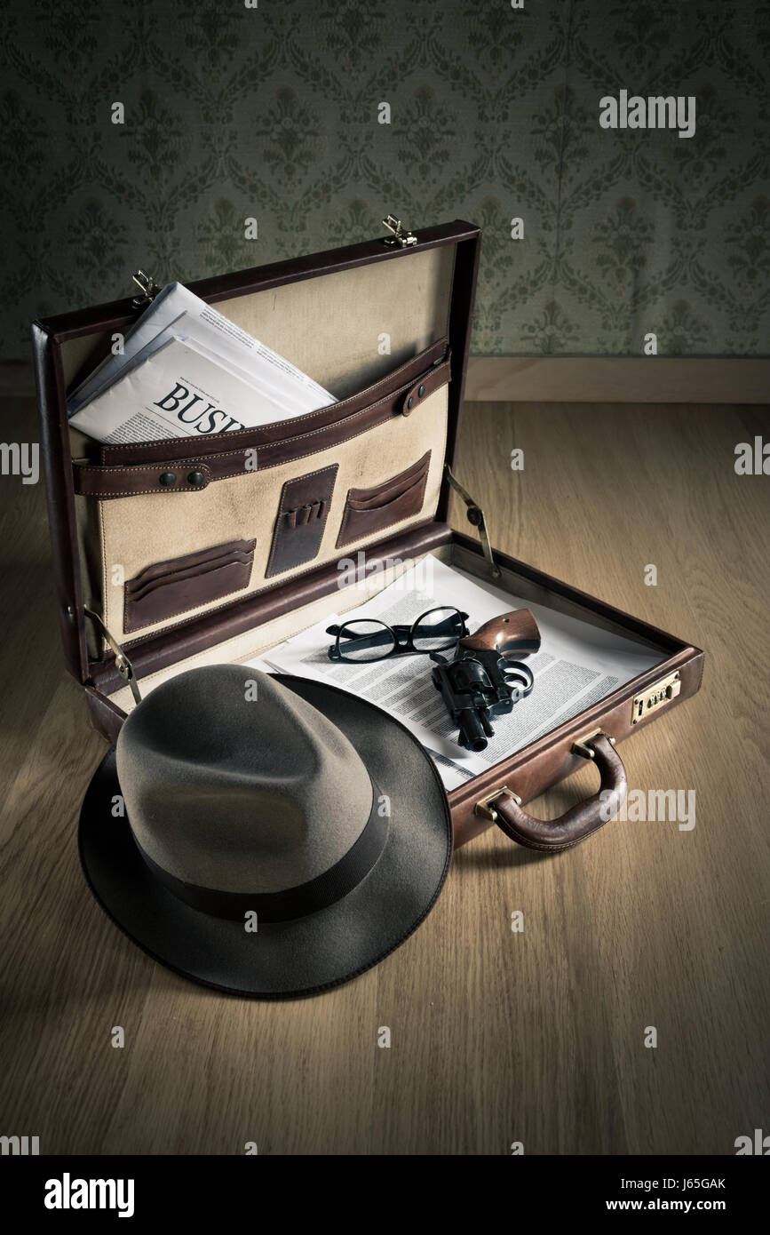 Open vintage leather briefcase with detective hat, revolver gun and