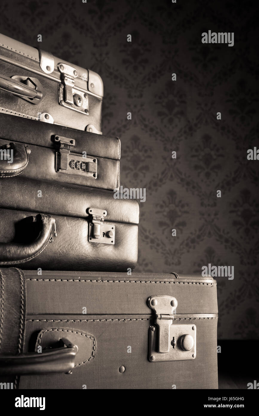 Pile of leather vintage suitcases, vintage wallpaper on background