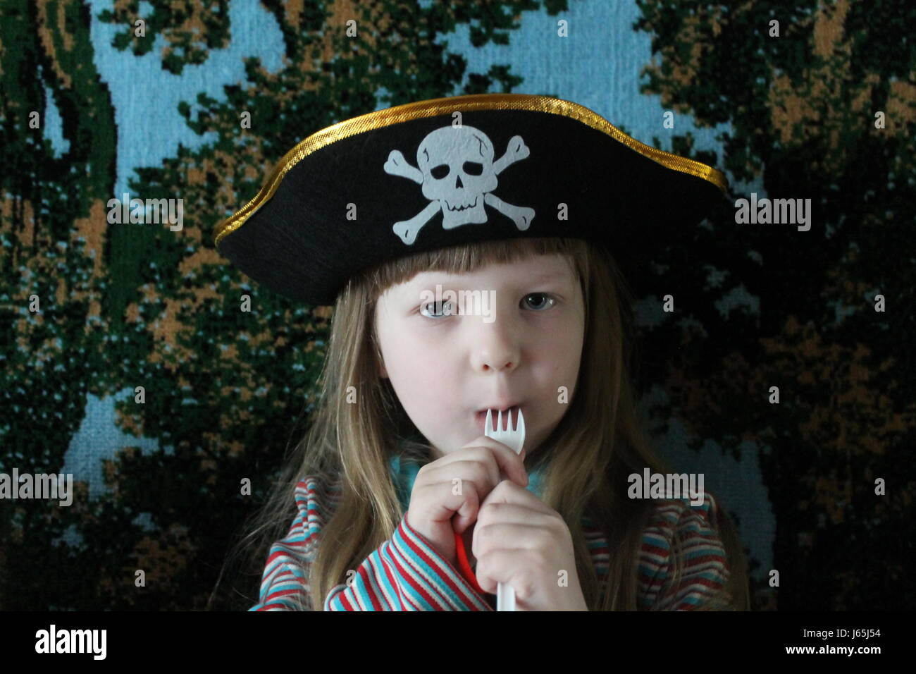 beautiful blonde girl with smiling face in hat of pirate with fork in mouth preapare to eat someone Stock Photo