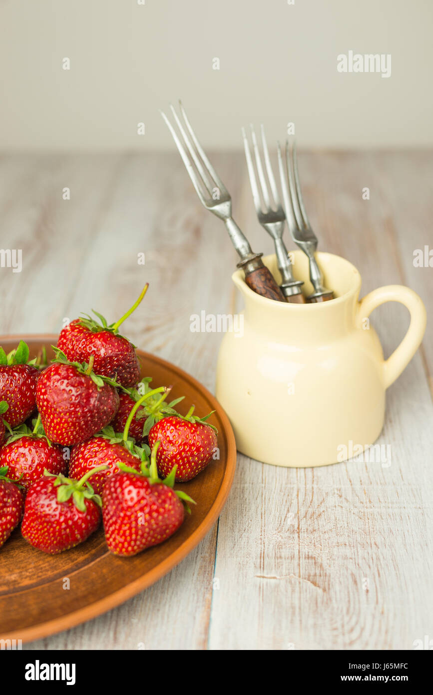 Plate with strawberries and forks in a pitcher on the table Stock Photo