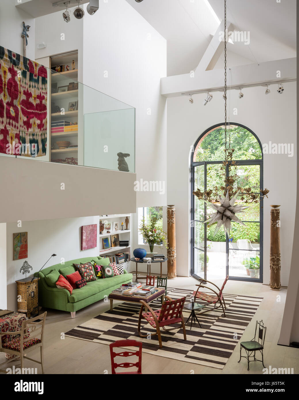 Triple-height living space with mezzanine and old textiles adding colour Stock Photo