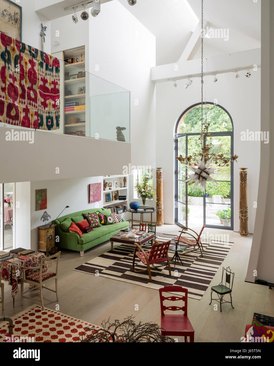 Triple-height living space with mezzanine and old textiles adding colour Stock Photo