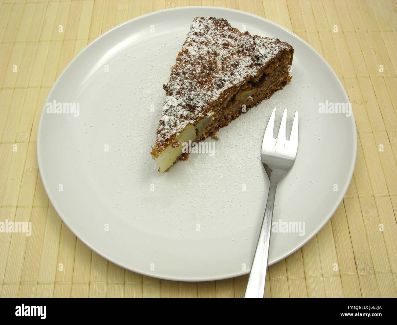 a piece of pear cake dusted with powdered sugar on white plate Stock Photo