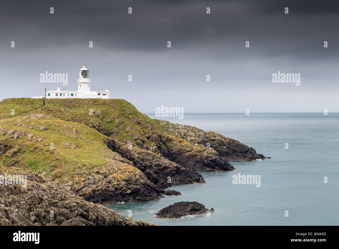 Lighthouse on a cliff with grey sky - Strumble Head, Wales, Great Britain, UK, Europe Stock Photo