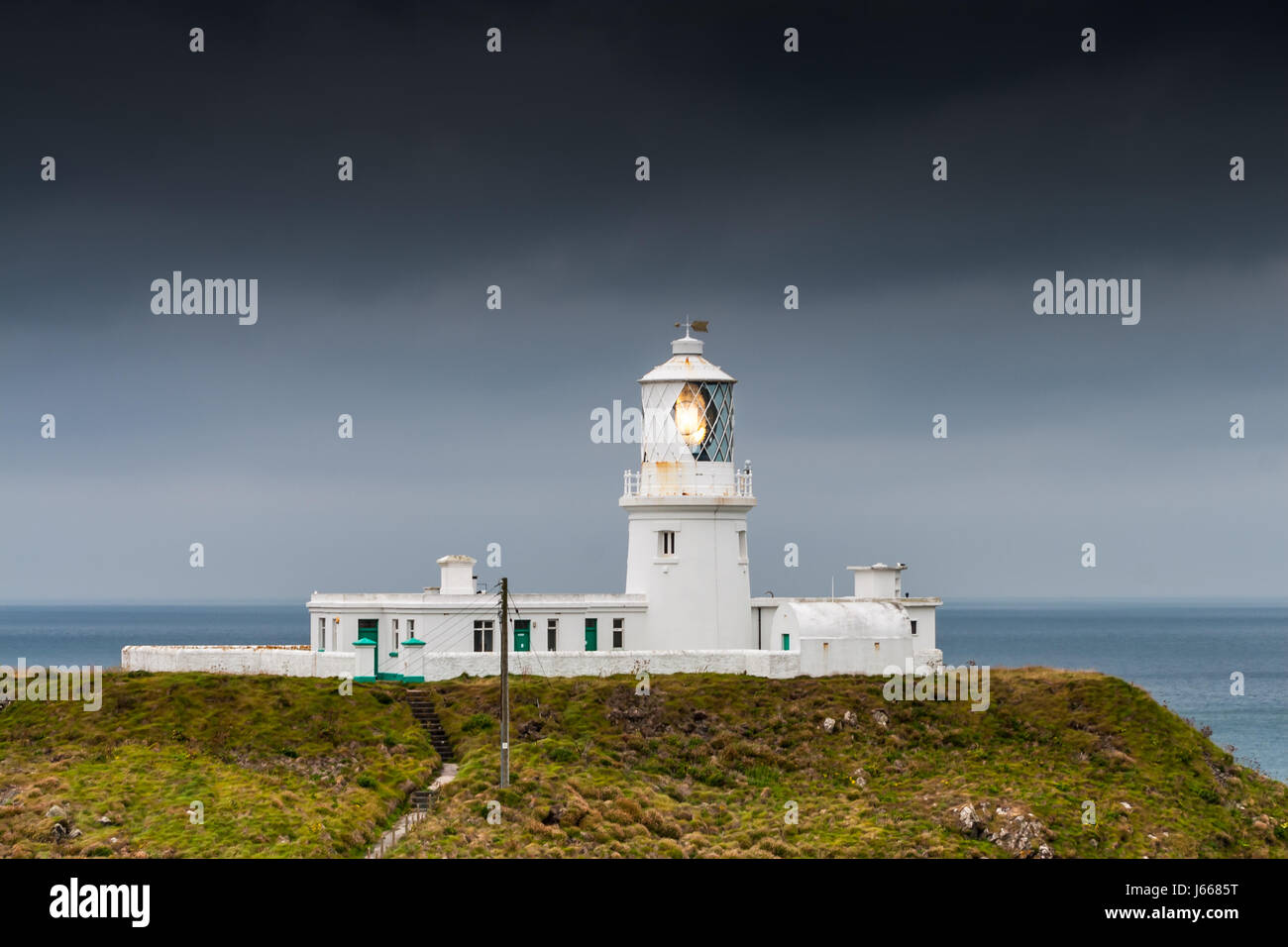 Lighthouse on a cliff with grey sky - Strumble Head, Wales, Great Britain, UK, Europe Stock Photo