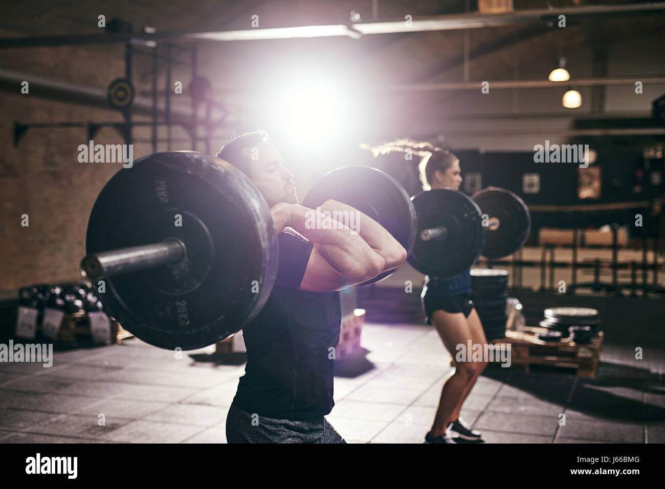 Strong people lifting big weight barbells in gym. Horizontal
