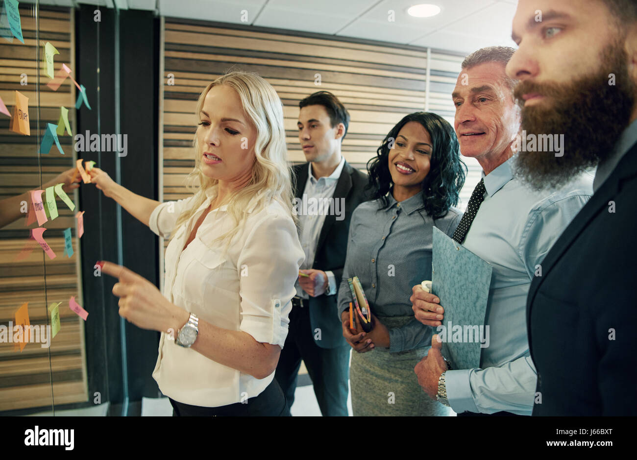 Group of business people brainstorming, putting stick notes on glass surface Stock Photo