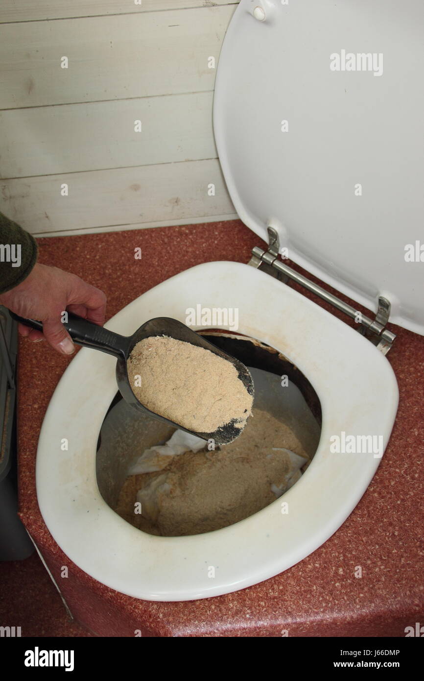 Sawdust is sprinkled into a working composting toilet located in a large English garden Stock Photo