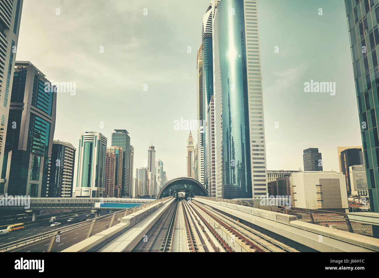 Retro toned photo of Dubai modern downtown seen from metro train, United Arab Emirates. Stock Photo