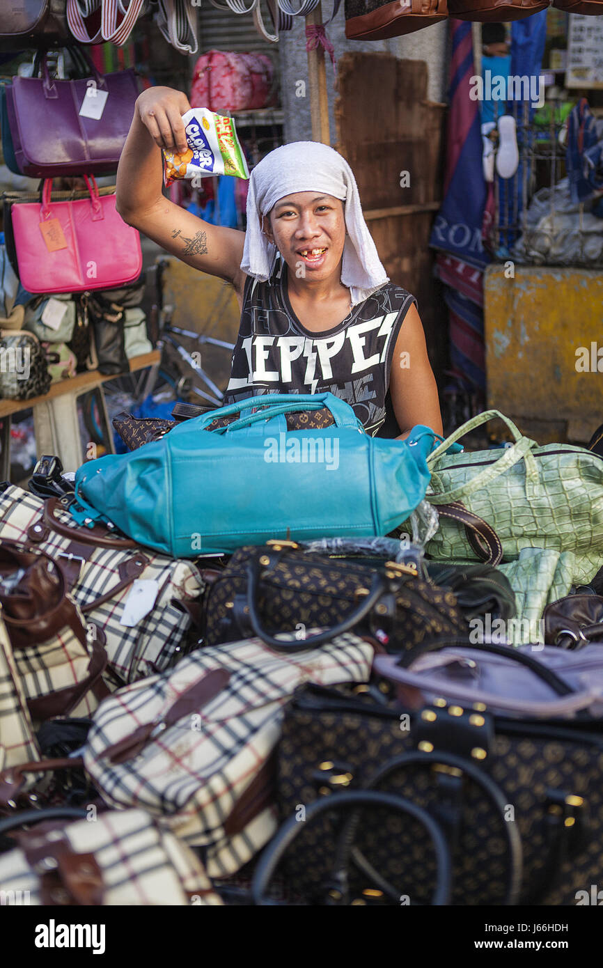 Filipino man sells fake brand name bags at the Baclaran street market in Parañaque City, Metro Manila, Luzon Island, Philippines. Stock Photo