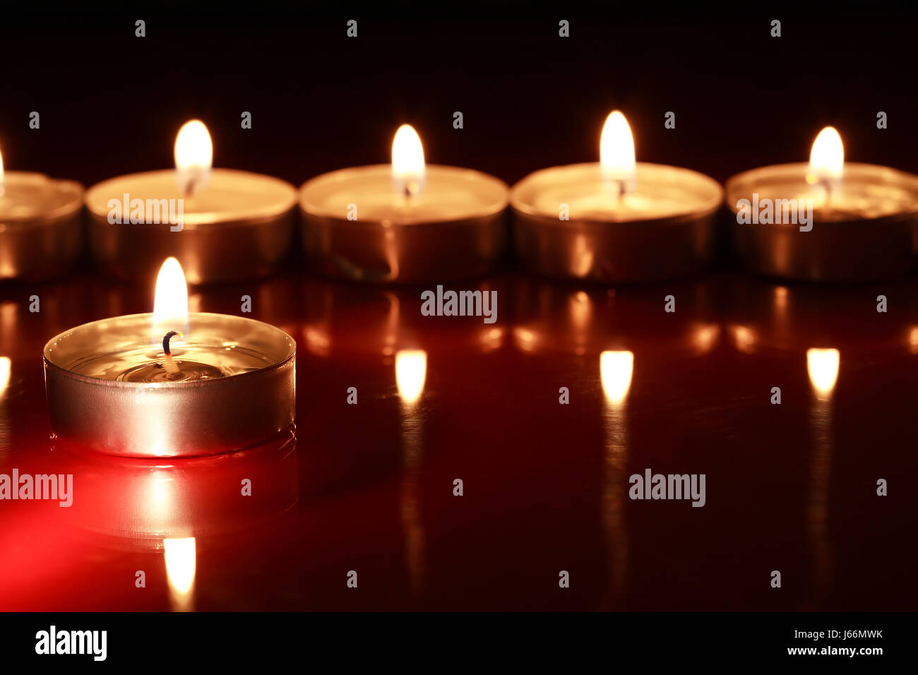 Set of lighting candles in a row on dark background with reflection ...