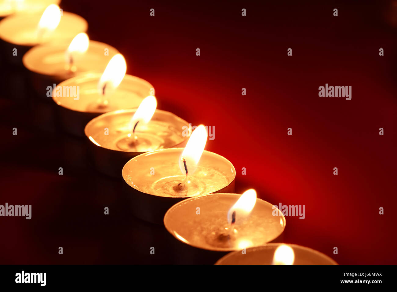 Set of lighting candles in a row on dark red background Stock Photo - Alamy