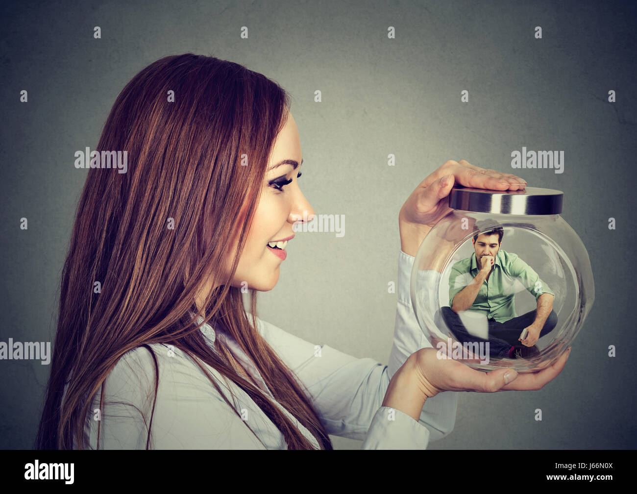 Woman holding a glass jar with imprisoned man in it Stock Photo