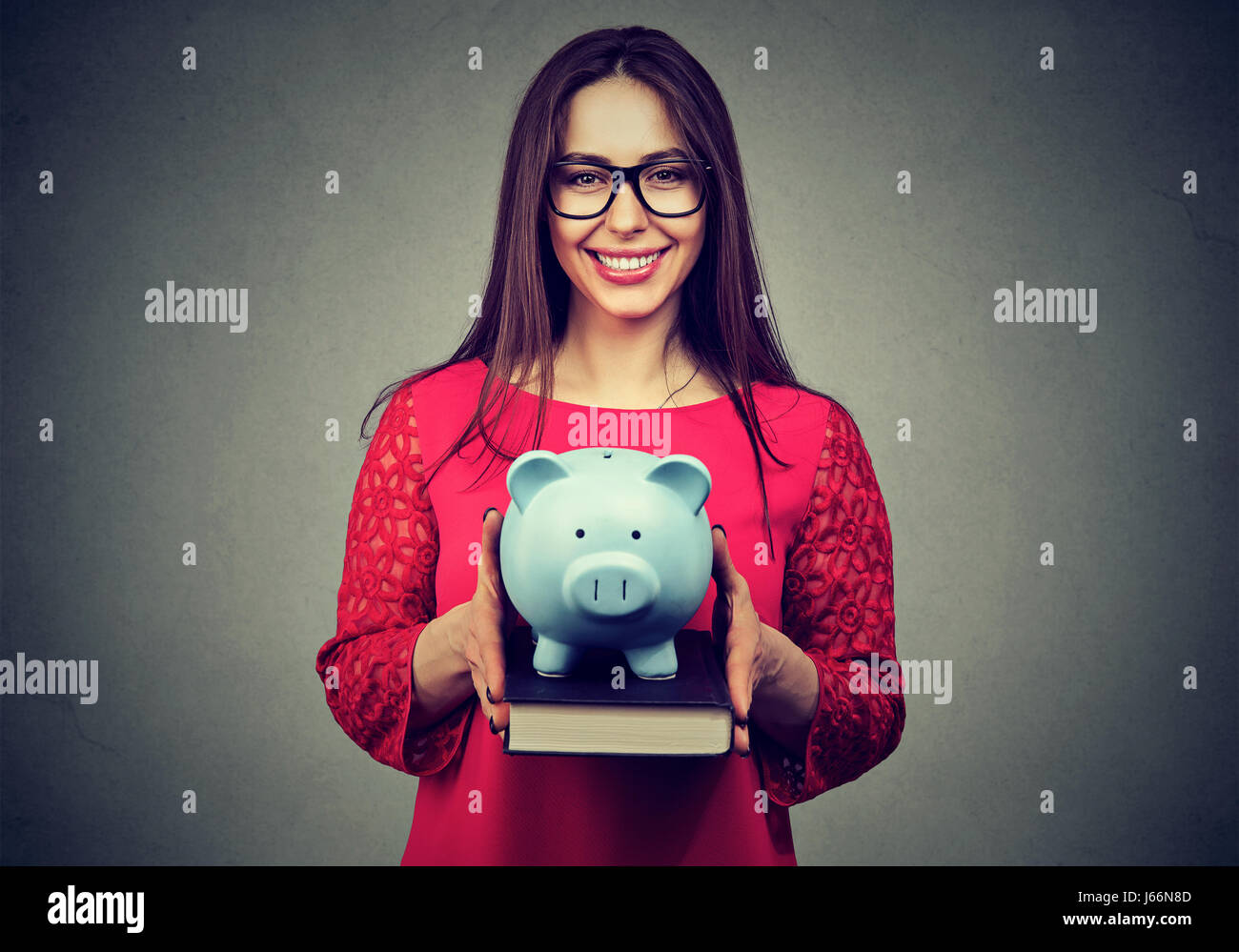 Smiling student, happy woman, holding books and piggy bank in hands. Value of education concept. College fund savings Stock Photo