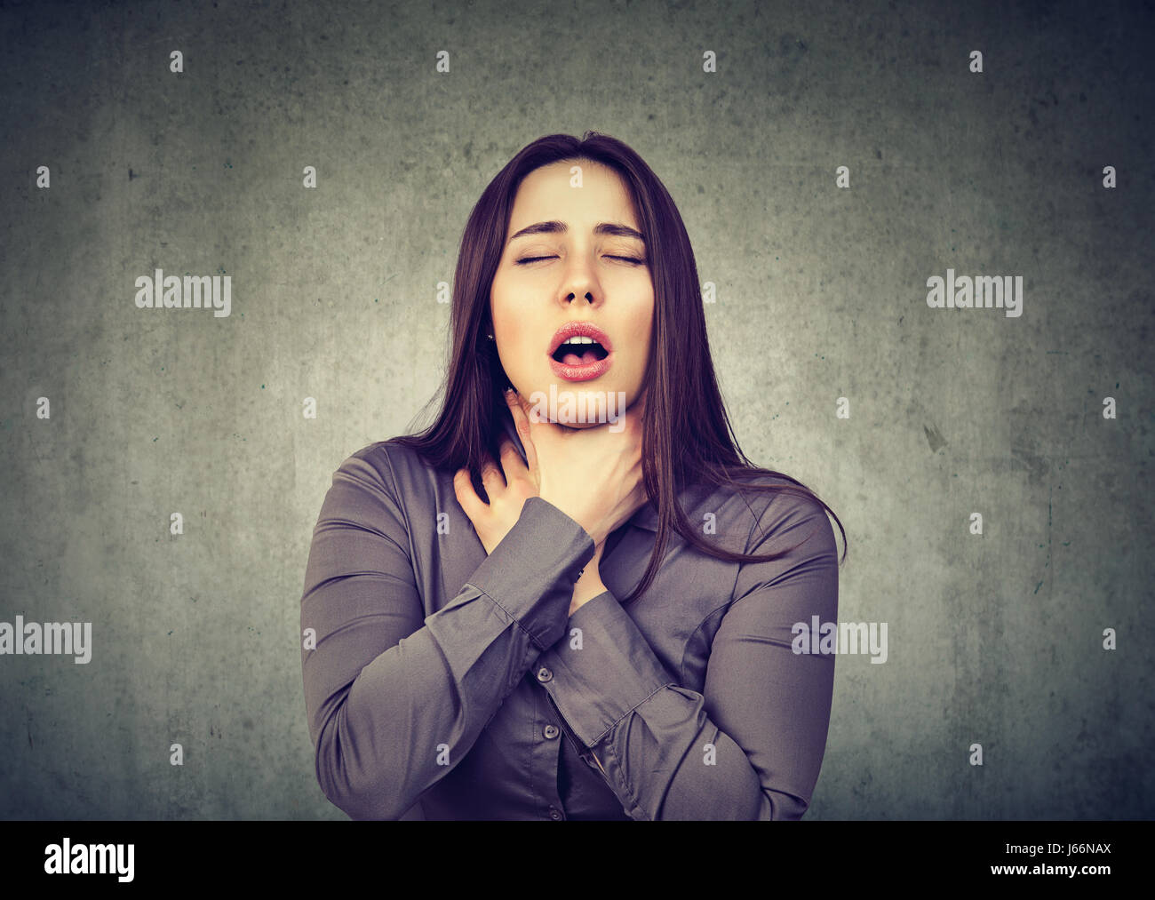 Young woman having asthma attack or choking can't breath suffering from respiration problems isolated on gray background Stock Photo