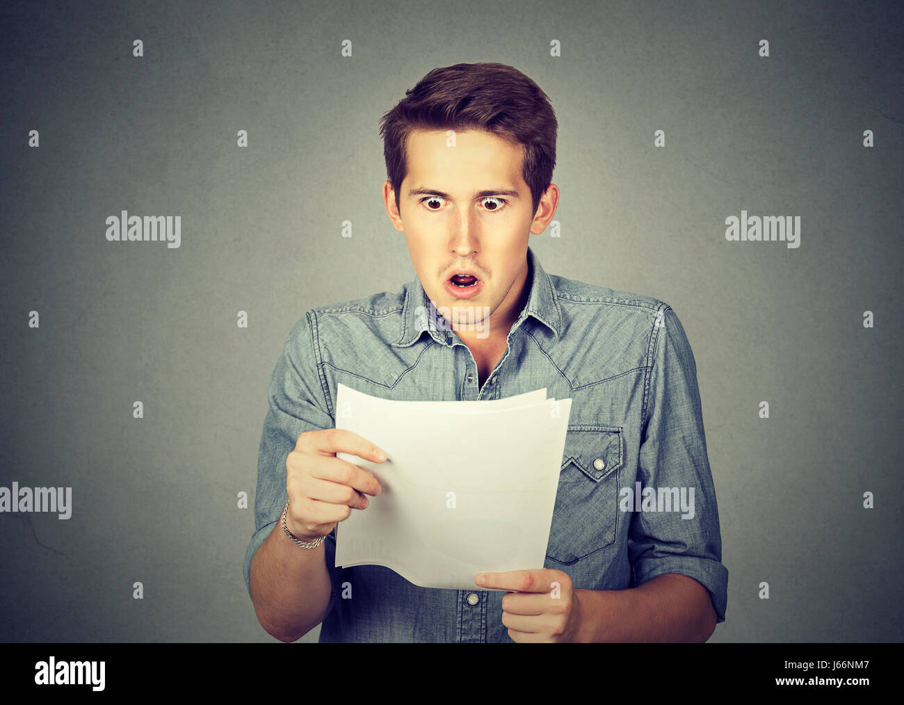 Shocked man holding some documents, isolated on gray background Stock ...