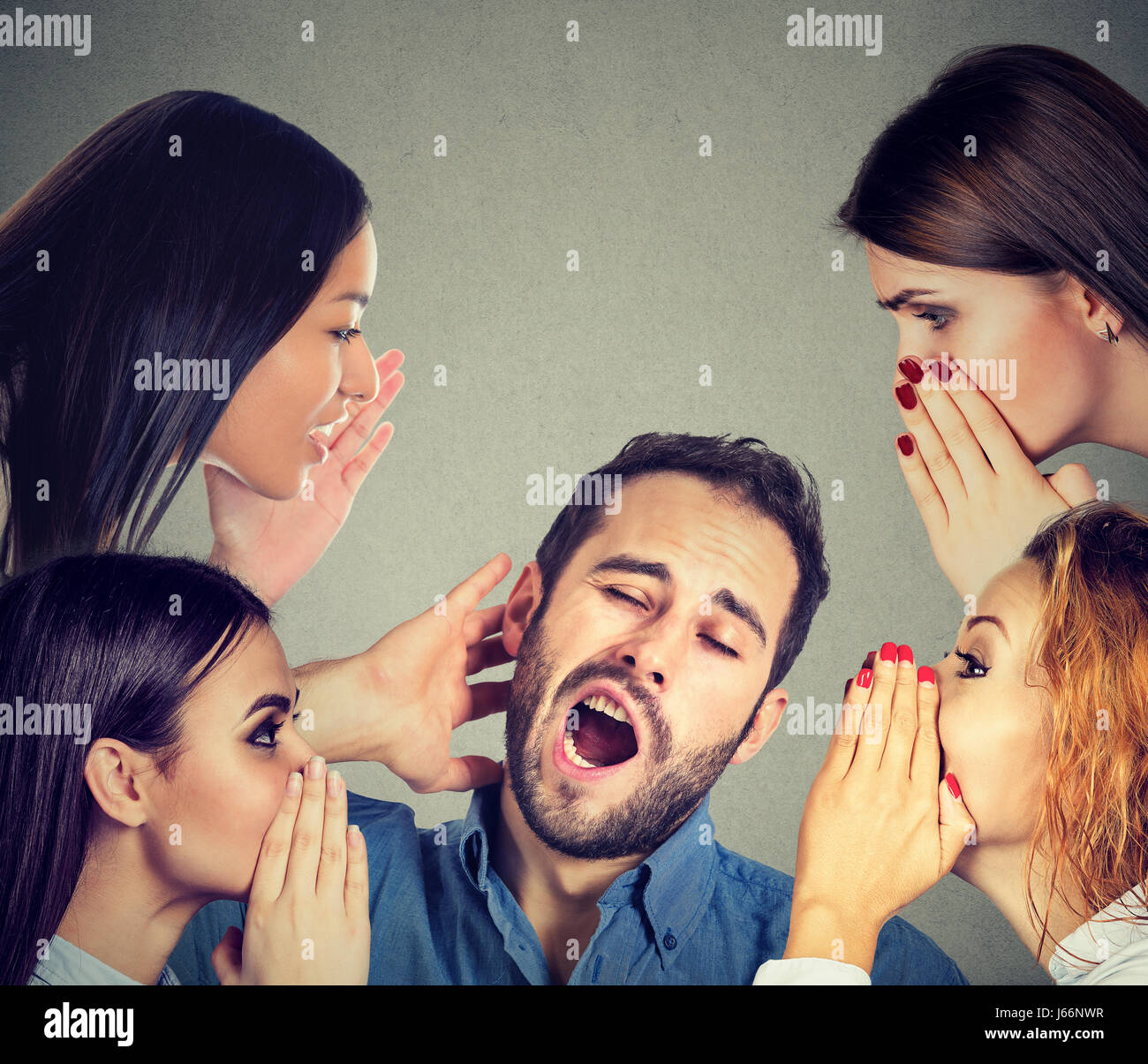 Four women whispering a secret latest gossip to a bored sleepy man Stock Photo