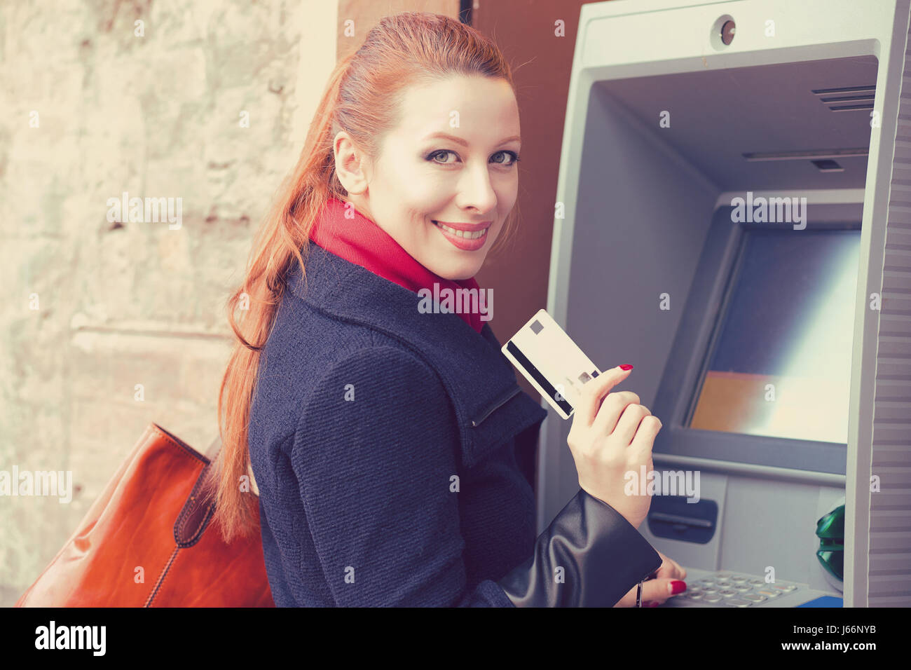 Young happy woman with bank card using ATM Stock Photo
